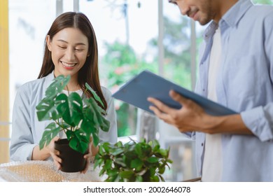 Happy Couple Woman, Man Asian Young Wife Unpack, Pack Carton Open Parcel, Holding Ceramic Plant Pot For Interior, Husband Check List Order In Cardboard Box. Moving, Preparing In New Home, Relocation