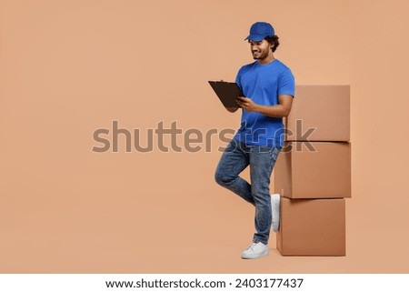 Happy courier with clipboard and stack of parcels on light brown background, space for text