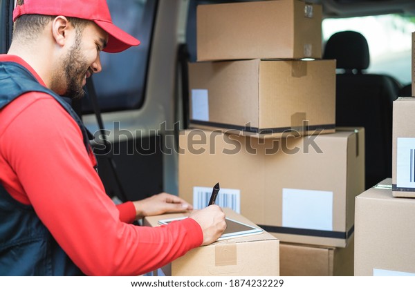 Happy courier man signing package delivery in van\
truck - Focus on pen