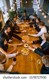 Happy Co-workers Celebrating While Company Party, Corporate Event. Young Caucasian People In Business Attire Talk, Drink Wine, Eat Snacks. Concept Of Office Culture, Teamwork, Friendship. Top View.