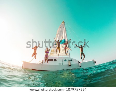 Happy crazy friends diving from sailing boat into the sea - Young people jumping inside ocean in summer vacation - Main focus on center guys - Travel and fun concept - Fisheye lens distortion