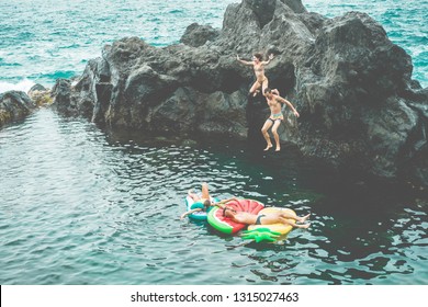 Happy Crazy Friends Jumping Inside Natural Sea Pool With Lilo - Young People Having Fun Cliff Diving Inside Ocean - Summer, Adventure, Travel Lifestyle And Vacation Concept - Main Focus On Top Guys