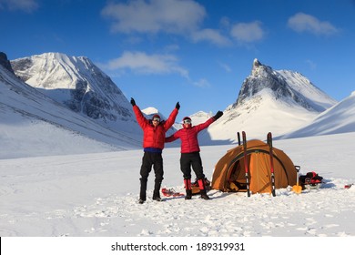 Happy cross country skiers at their tent during a winter trekking in the mountains of Lapland.