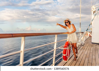 Happy cruise vacation fun travel woman pointing watching whales or wildlife sighting from deck of boat on Europe summer destination cruising vacation holiday. Luxury relaxation getaway.