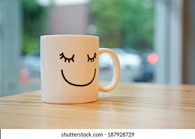 Happy cup on wood table with black polka dot tablecloth. Concept about happiness.                        