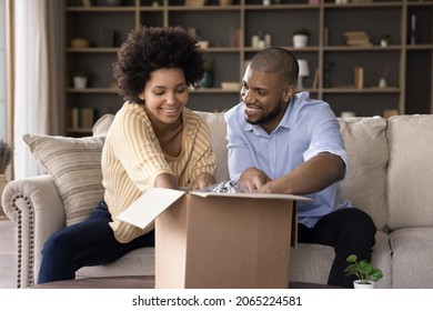 Happy Curious Young African American Family Couple Opening Big Carton Box, Enjoying Unpacking Internet Store Order Together At Home, Satisfied With Fast Delivery Service, Online Shopping Concept.