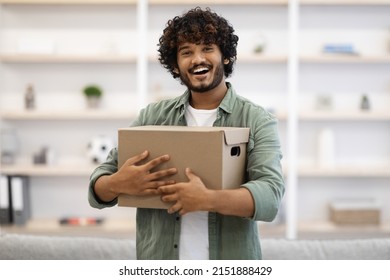 Happy curly bearded young indian man in casual embracing box with something and smiling, home interior, making order on Internet with delivery, copy space. Delivery service, shipment concept - Shutterstock ID 2151888429