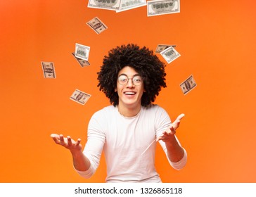 Happy Curly Black Guy Enjoying Rain Of Money, Orange Studio Background