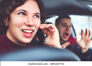 Happy curly haired girl talking on mobile phone while driving car. man in next seat is terrified of impending accident. Be distracted while driving the vehicle. - Shutterstock ID 1896347755