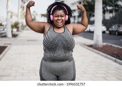 Happy curvy african woman doing workout routine outdoor at city park - Focus on face