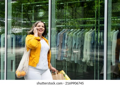 Happy curvy woman with shopping bags talking on mobile phone enjoying in shopping. Consumerism, shopping, lifestyle concept - Powered by Shutterstock