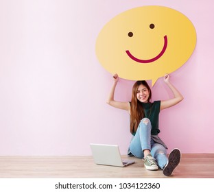 Happy Customer Concept. Review And Feedback Her Experience For Satisfaction Survey Online. Young Female In Cheerful Posture, Raise Up Speech Bubble With Smiley Face. Sit On The Floor With Laptop