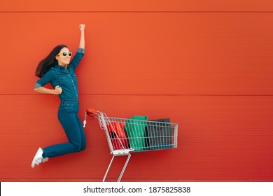 Happy Customer Jumping With Joy In Front Of A Supermarket. Super Excited Female Client Having A Great Shopping Experience
