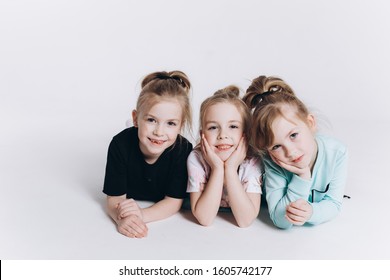 Happy Cute Adorable Blondie Triplets Girls Posing In Studio Together On Isolated Background. Childhood, Children, Twins Concept. Smiling Girls Playing Together