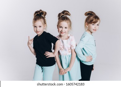 Happy Cute Adorable Blondie Triplets Girls Posing In Studio Together On Isolated Background. Childhood, Children, Twins Concept. Smiling Girls Playing Together