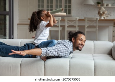 Happy cute African American daughter girl riding cheerful dads back, playing pirate sailing boat, ship, looking forward through toy spyglass, imagining discovery. Dad and kid enjoying funny game - Powered by Shutterstock