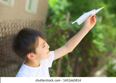 Happy Cute Asian Child Boy Playing With Paper Airplane Outdoors