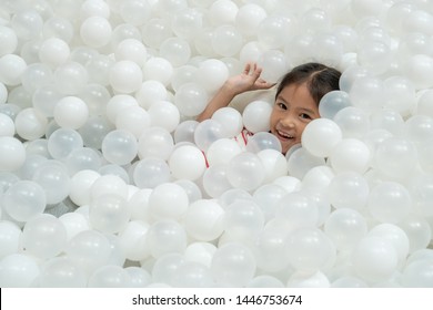 Happy cute asian child girl having fun to play with white plastic balls in the playground
