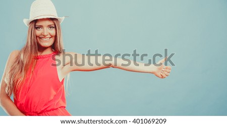 Happy cute attractive young woman girl in red shirt and straw hat in studio on blue showing thumb up gesture. Summer female fashion vogue. 