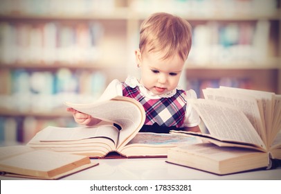 Happy cute baby girl reading a book in a library