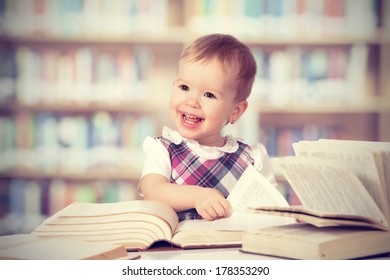 Happy cute baby girl reading a book in a library
