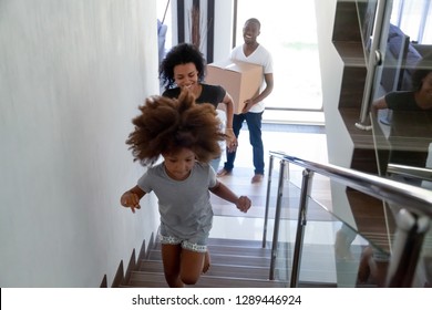 Happy cute black child running up stairs moving in two story modern house with parents carrying boxes, excited kid having fun going upstairs enjoying relocation into new home, african family mortgage - Powered by Shutterstock