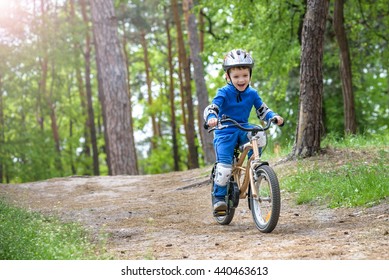 Happy Cute Blond Kid Boy Having Fun His First Bike On Sunny Summer Day, Outdoors. Happy Child Making Sports. Active Leisure For Children.Kid Boy Wear Safety Helmet. Boy Is Smiling And Cicling.