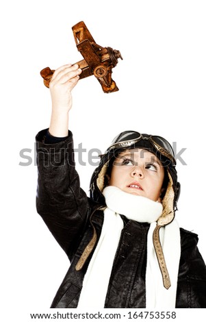 Happy cute boy dressed like a World War II pilot playing with wooden airplane toy isolated on white background.Vintage look