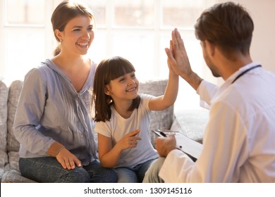 Happy Cute Child Girl Giving High Five To Male Pediatrician Welcoming Little Patient With Mom At Consultation, Trusting Kid And Doctor Celebrate Good Checkup Medical Results Or Getting Cured Healed