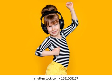 Happy Cute Girl Child 5-6 Years Old With Headphones On A Yellow Background