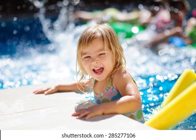 Happy Cute Girl In Outdoor Swimming Pool Has Fun With Splash And Toys