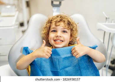 Happy cute little boy in dental ofiice showing thumbs up after treatment