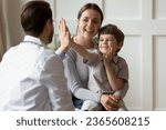 Happy cute little boy giving high five to pediatrician, friendly doctor greeting preschool patient at medical appointment, good checkup result, young mum and son visiting gp in hospital