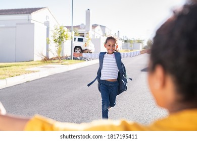 Happy Cute Little Girl Running With Outstretched Arms Towards Mother. Elementary Indian Student Kid Running In The Driveway Into Hands Of African Mother To Hug Her After School. Indian Schoolgirl.