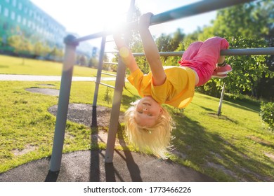 Happy Cute Little Girl Upside Down On Monkey Bars