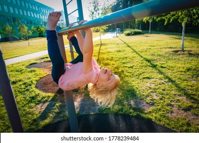 Happy Cute Little Girl Upside Down On Monkey Bars