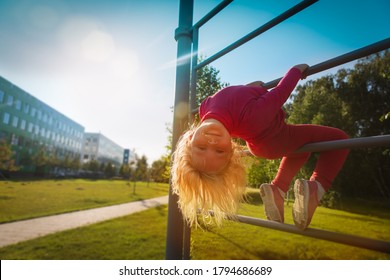 Happy Cute Little Girl Upside Down On Monkey Bars