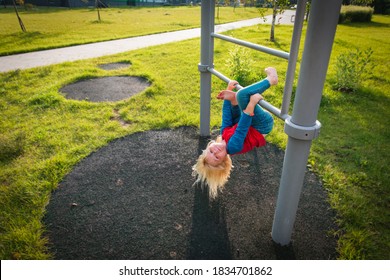 Happy Cute Little Girl Upside Down On Monkey Bars.