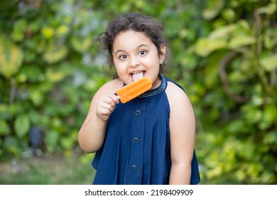 Happy Cute Little Indian Asian Girl Child Enjoying Ice Lolly Or Ice Cream At Park.