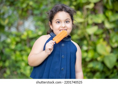 Happy Cute Little Indian Girl Child Enjoying Ice Lolly Or Ice Cream At Park.