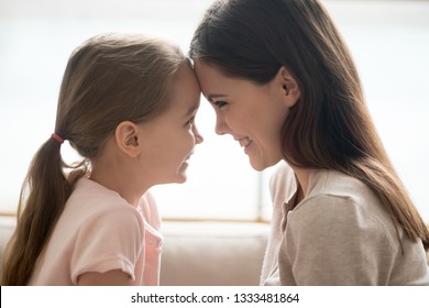 Happy Cute Little Kid Girl And Smiling Young Mother Tenderly Touching Foreheads, Loving Mom And Child Daughter Having Fun Playing Bonding, Family Love Connection Affection Concept, Side Profile View