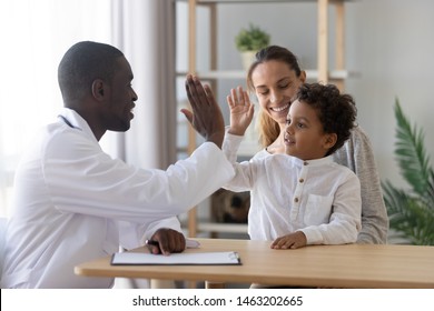 Happy Cute Mixed Race Child Boy Give High Five To African Man Pediatrician Welcome Little Patient And Mom At Consultation, Trusting Kid With Doctor Celebrate Good Medical Health Care Treatment Result