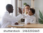 Happy cute multiracial child boy give high five to african man pediatrician welcome little patient and mom at consultation trusting kid with doctor celebrate good medical health care treatment result