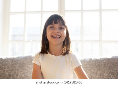 Happy Cute Preschooler Girl Sit On Couch Talking On Web Cam  Conversation, Funny Little Child Vlogger Shoot Vlog Speak Chat With Subscribers, Smiling Small Kid Record Video On Sofa At Home