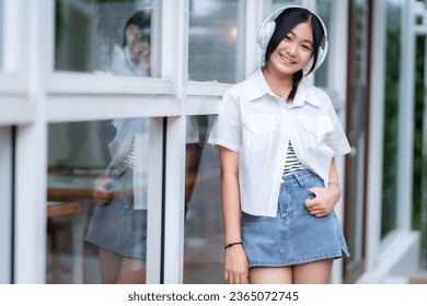 Happy of cute smiles Asian of attractive young Cute little girl wearing white wireless headphones and listening music enjoying favourite audio at the cafe on vacation at a coffee shop. - Shutterstock ID 2365072745