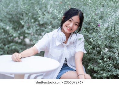 Happy of cute smiles Asian of attractive young Cute little girl wearing white wireless headphones and listening music enjoying favourite audio at the cafe on vacation at a coffee shop. - Shutterstock ID 2365072767