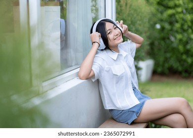 Happy of cute smiles Asian of attractive young Cute little girl wearing white wireless headphones and listening music enjoying favourite audio at the cafe on vacation at a coffee shop. - Shutterstock ID 2365072991