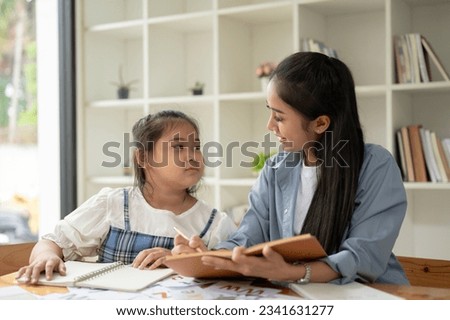 A happy and cute young Asian girl is enjoying studying English with a teacher at home. private tutor, home school, babysitting