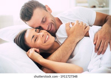 Happy cute young beautiful couple in love hugging each other and having fun in the big white bed after dream