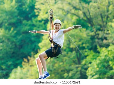 Happy, cute, young boy in white t shirt and helmet having fun and playing at adventure park, flying on the ropes.  Hobby, active lifestyle concept - Shutterstock ID 1150672691
